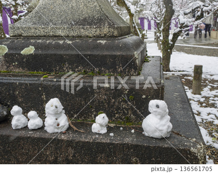 灯籠の傍らで佇む雪だるま、冬の京都の境内 灯籠の傍らで佇む雪だるま、冬の京都の境内 136561705