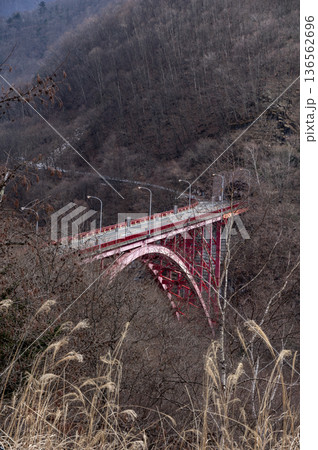 冬の奥秩父の彩甲斐街道に架かる赤いアーチ橋「豆焼橋」と山々の風景 136562696