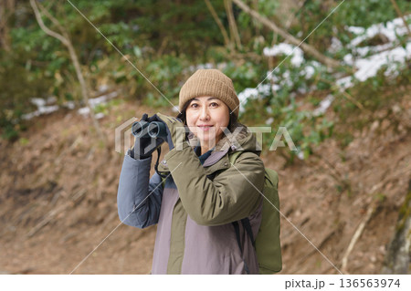 冬の野外で双眼鏡を持ち散策する女性 冬の野外で双眼鏡を持ち散策する女性 136563974