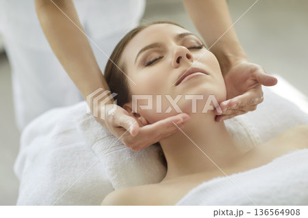 Massage and facial skin treatment for woman by therapist hands touching chin Massage and facial skin treatment for woman by therapist hands touching chin 136564908