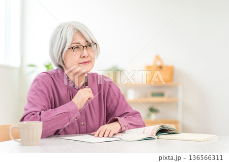 教材を見ながら勉強をするシニア女性 136566311