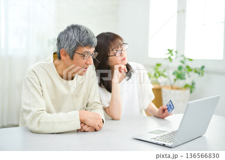リビングでパソコンとカードを見る60代の夫婦 リビングでパソコンとカードを見る60代の夫婦 136566830