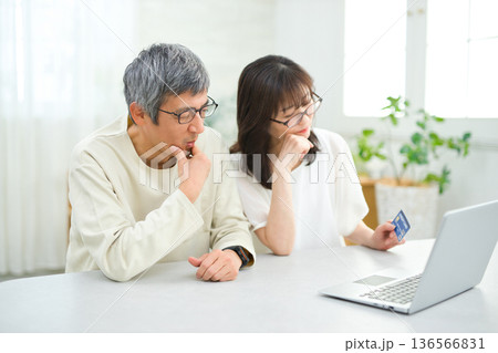 リビングでパソコンとカードを見る60代の夫婦 136566831