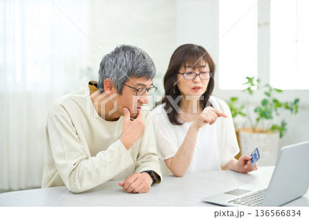 リビングでパソコンとカードを見る60代の夫婦 136566834