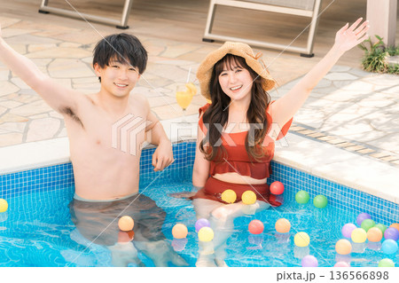 リゾート・バカンスでプールに入って遊ぶ若いアジア人カップル 136566898