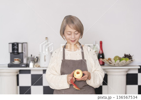 キッチンでりんごの皮をむくシニア女性 キッチンでりんごの皮をむくシニア女性 136567534