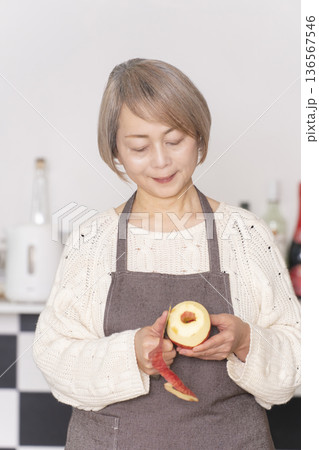 キッチンでりんごの皮をむくシニア女性 キッチンでりんごの皮をむくシニア女性 136567546