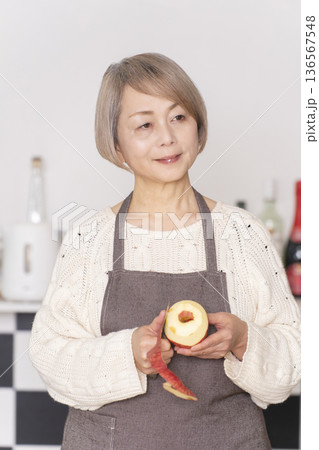 キッチンでりんごの皮をむくシニア女性 キッチンでりんごの皮をむくシニア女性 136567548