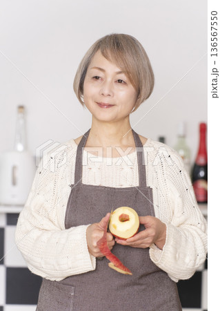 キッチンでりんごの皮をむくシニア女性 キッチンでりんごの皮をむくシニア女性 136567550