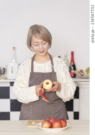 キッチンでりんごの皮をむくシニア女性 キッチンでりんごの皮をむくシニア女性 136567552