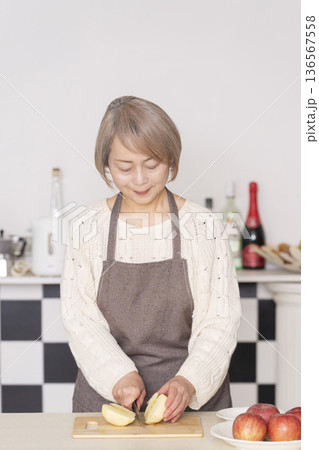 キッチンでりんごの皮をむくシニア女性 キッチンでりんごの皮をむくシニア女性 136567558