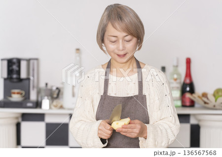 キッチンでりんごの皮をむくシニア女性 キッチンでりんごの皮をむくシニア女性 136567568