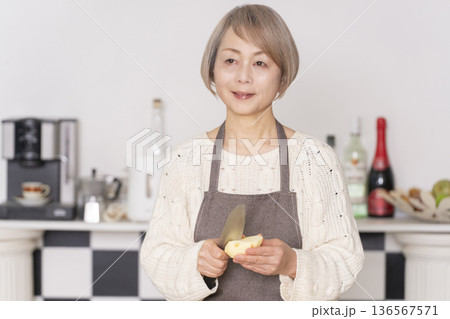 キッチンでりんごの皮をむくシニア女性 キッチンでりんごの皮をむくシニア女性 136567571