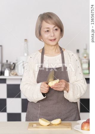 キッチンでりんごの皮をむくシニア女性 キッチンでりんごの皮をむくシニア女性 136567574