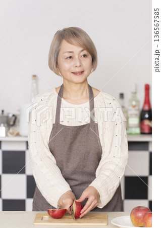 キッチンでりんごの皮をむくシニア女性 キッチンでりんごの皮をむくシニア女性 136567585