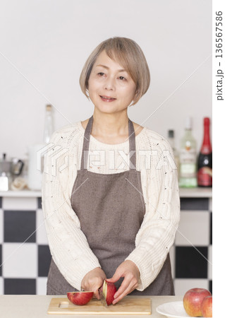 キッチンでりんごの皮をむくシニア女性 キッチンでりんごの皮をむくシニア女性 136567586
