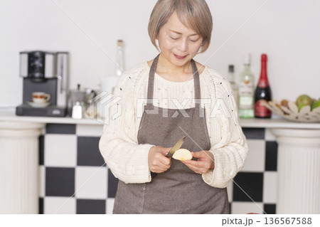 キッチンでりんごの皮をむくシニア女性 キッチンでりんごの皮をむくシニア女性 136567588