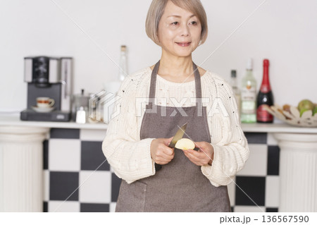 キッチンでりんごの皮をむくシニア女性 キッチンでりんごの皮をむくシニア女性 136567590