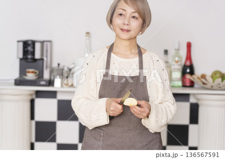 キッチンでりんごの皮をむくシニア女性 136567591