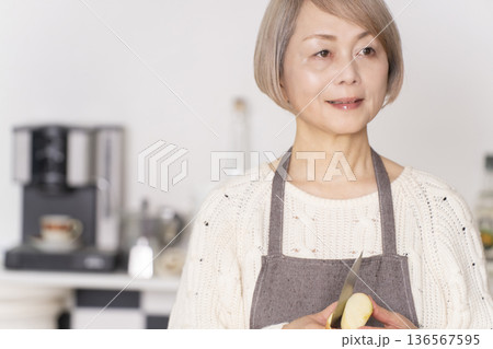 キッチンでりんごの皮をむくシニア女性 キッチンでりんごの皮をむくシニア女性 136567595