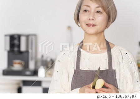 キッチンでりんごの皮をむくシニア女性 136567597