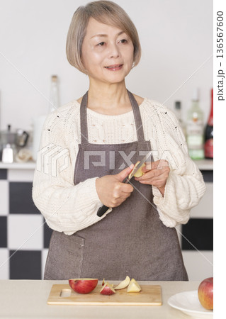 キッチンでりんごの皮をむくシニア女性 キッチンでりんごの皮をむくシニア女性 136567600