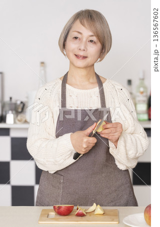 キッチンでりんごの皮をむくシニア女性 キッチンでりんごの皮をむくシニア女性 136567602