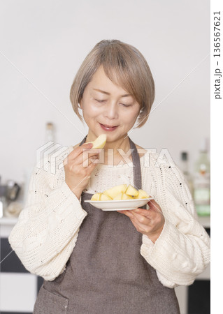 キッチンでりんごの皮をむくシニア女性 キッチンでりんごの皮をむくシニア女性 136567621
