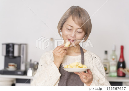 キッチンでりんごの皮をむくシニア女性 キッチンでりんごの皮をむくシニア女性 136567627
