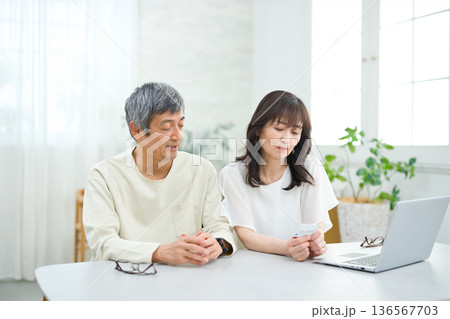 リビングでパソコンとカードを見る60代の夫婦 リビングでパソコンとカードを見る60代の夫婦 136567703