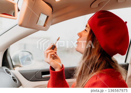Woman makeup car. Young woman applies lip gloss in car using vanity mirror. 136567975