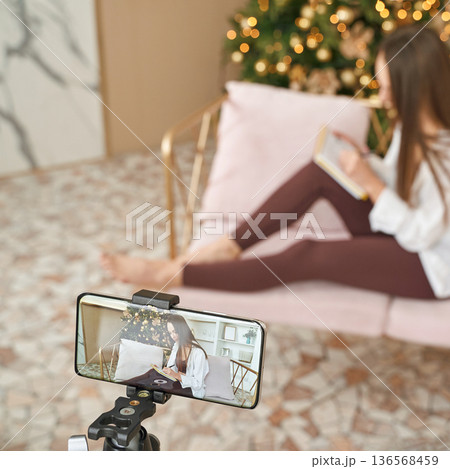 Young caucasian female recording video on smartphone while reading Young caucasian female recording video on smartphone while reading 136568459