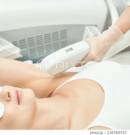 Young caucasian female undergoing laser hair removal on armpit in professional Young caucasian female undergoing laser hair removal on armpit in professional 136568535