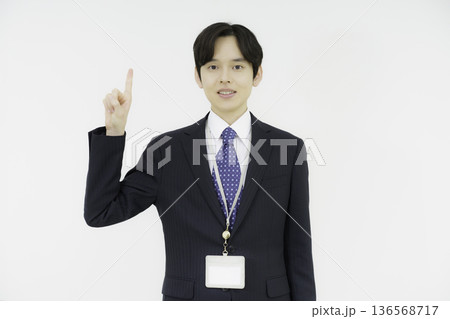 白背景の指さしポーズをするカメラ目線のスーツを着た若い日本人男性のポートレート 白背景の指さしポーズをするカメラ目線のスーツを着た若い日本人男性のポートレート 136568717