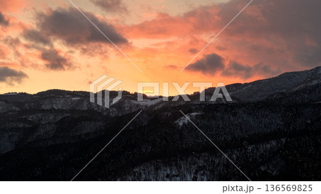 雪山に沈む夕日と冬の空を上昇するドローン空撮 136569825