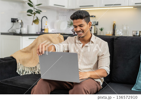 Indian man opens laptop starts project launches app begins typing with focus and sets new task list Indian man opens laptop starts project launches app begins typing with focus and sets new task list 136572910