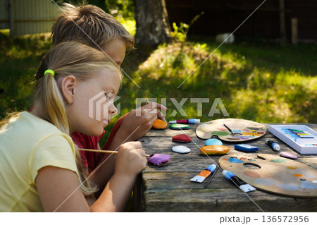 Using brushes and imagination, children turn smooth rocks into treasures, perfect as loving handmade gifts. Using brushes and imagination, children turn smooth rocks into treasures, perfect as loving handmade gifts. 136572956