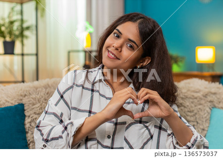 Indian woman forms heart hands blowing kiss toward camera expressing love affection joyful greeting Indian woman forms heart hands blowing kiss toward camera expressing love affection joyful greeting 136573037