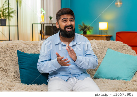 Indian man claps hands celebrates online game win happy news success great applause indoors victory Indian man claps hands celebrates online game win happy news success great applause indoors victory 136573905