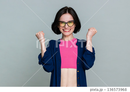 Young woman celebrating win with joyful smile expressing happiness success achievement excitement 136573968
