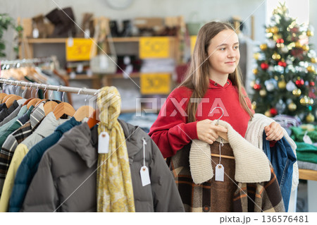 Teenage girl chooses coat or jacket in clothing store 136576481