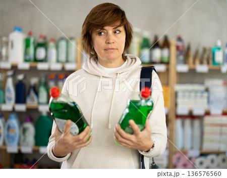 Adult woman chooses dishwashing detergent in store Adult woman chooses dishwashing detergent in store 136576560