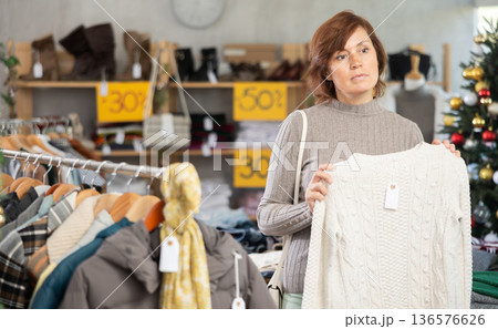 Adult woman chooses sweater in clothing store 136576626
