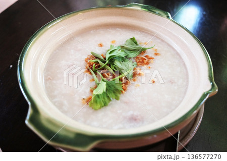 Rice porridge machine served in a white bowl with minced pork and coriander and fried garlic sprinkled on top 136577270