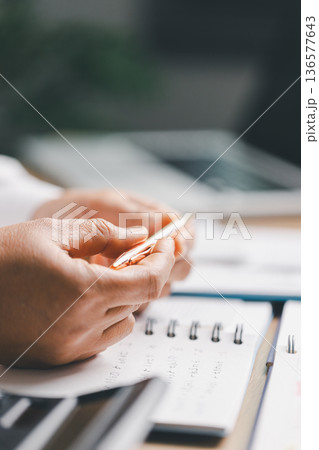 Hand writing notes in a notebook beside a calculator on office desk for budgeting and accounting. Personal finance planning, expense tracking, tax calculation, soft focus background, copy space. Hand writing notes in a notebook beside a calculator on office desk for budgeting and accounting. Personal finance planning, expense tracking, tax calculation, soft focus background, copy space. 136577643