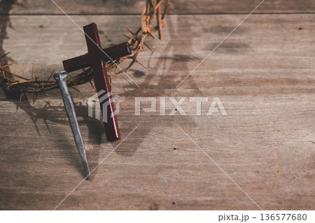 Wooden cross, crown of thorns and three iron nails on rustic wooden table, warm dramatic light and copy space, symbolizing crucifixion, sacrifice, Holy Week, Good Friday and Easter. Wooden cross, crown of thorns and three iron nails on rustic wooden table, warm dramatic light and copy space, symbolizing crucifixion, sacrifice, Holy Week, Good Friday and Easter. 136577680