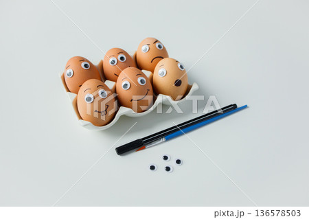 Funny handmade Easter emoji eggs with big eyes on white background. Creative decoration before Easter holiday Funny handmade Easter emoji eggs with big eyes on white background. Creative decoration before Easter holiday 136578503