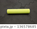 Yellow textured foam roller on gray puzzle mat for fitness and muscle relief 136578685