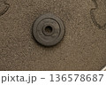Single black weight plate on rough textured surface 136578687
