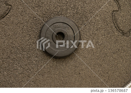 Single black weight plate on rough textured surface Single black weight plate on rough textured surface 136578687